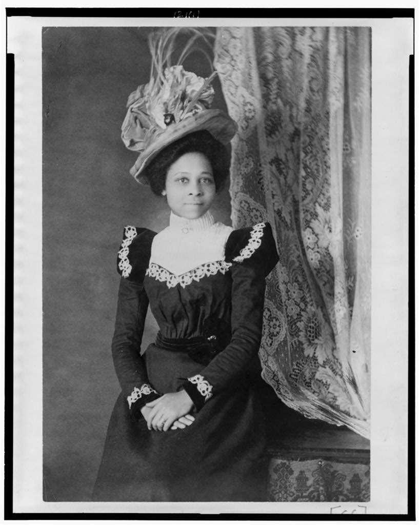 Young African American woman, three-quarter length portrait, facing slightly right, with hands folded on her lap, Attribution to Askew from Photography on the color line